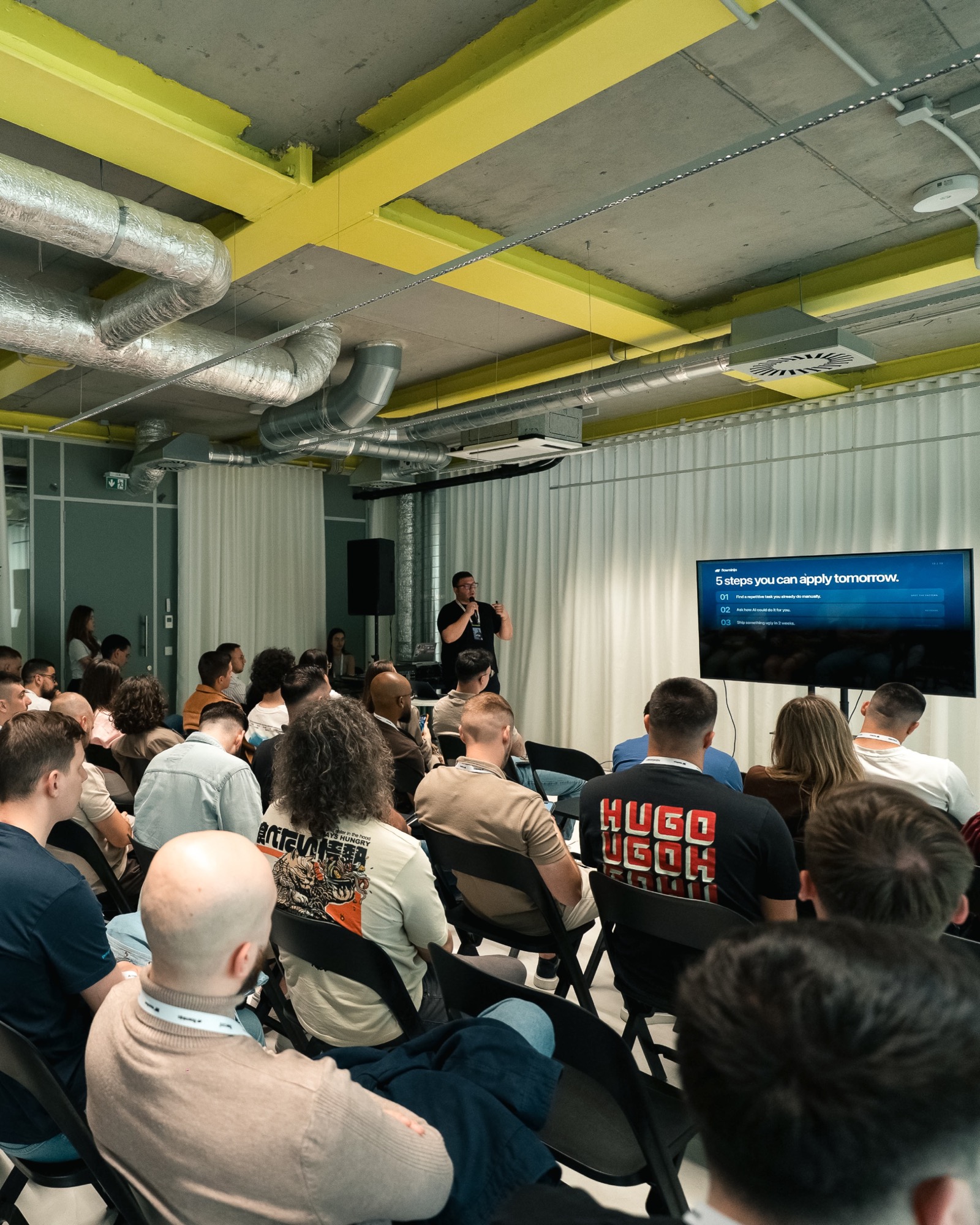 A packed side room, the speaker at the front beside a slide headed "5 steps you can apply tomorrow".