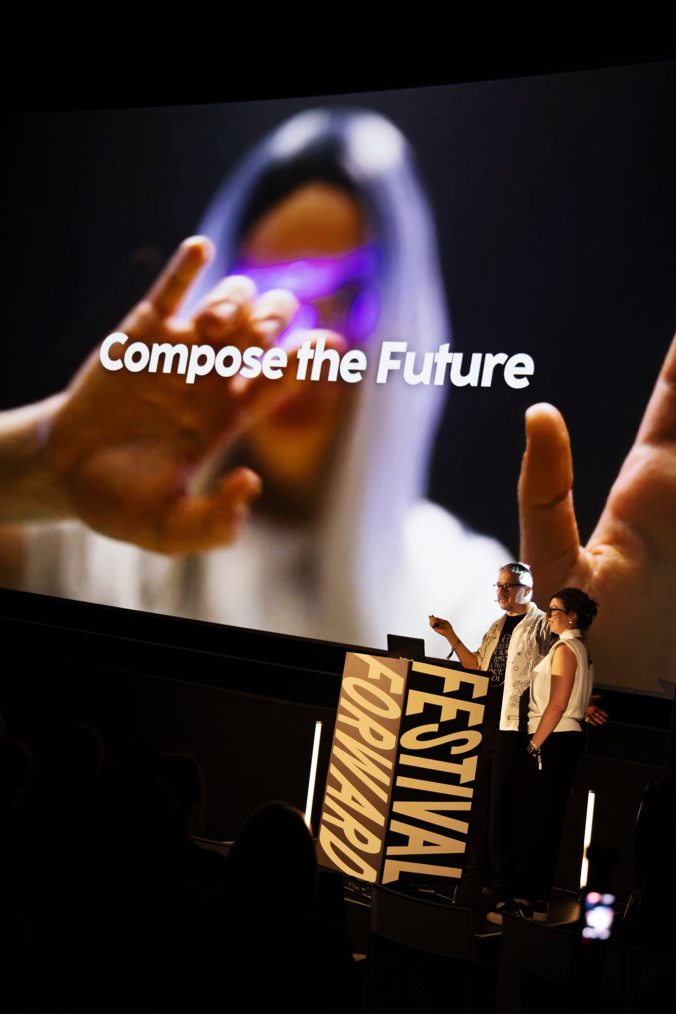Two speakers on stage in front of a slide reading "Compose the Future".