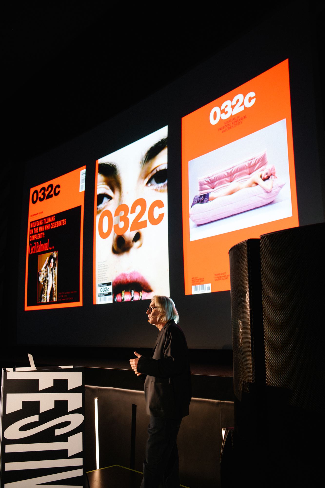 A speaker walking the room through three 032c magazine covers on the big screen.