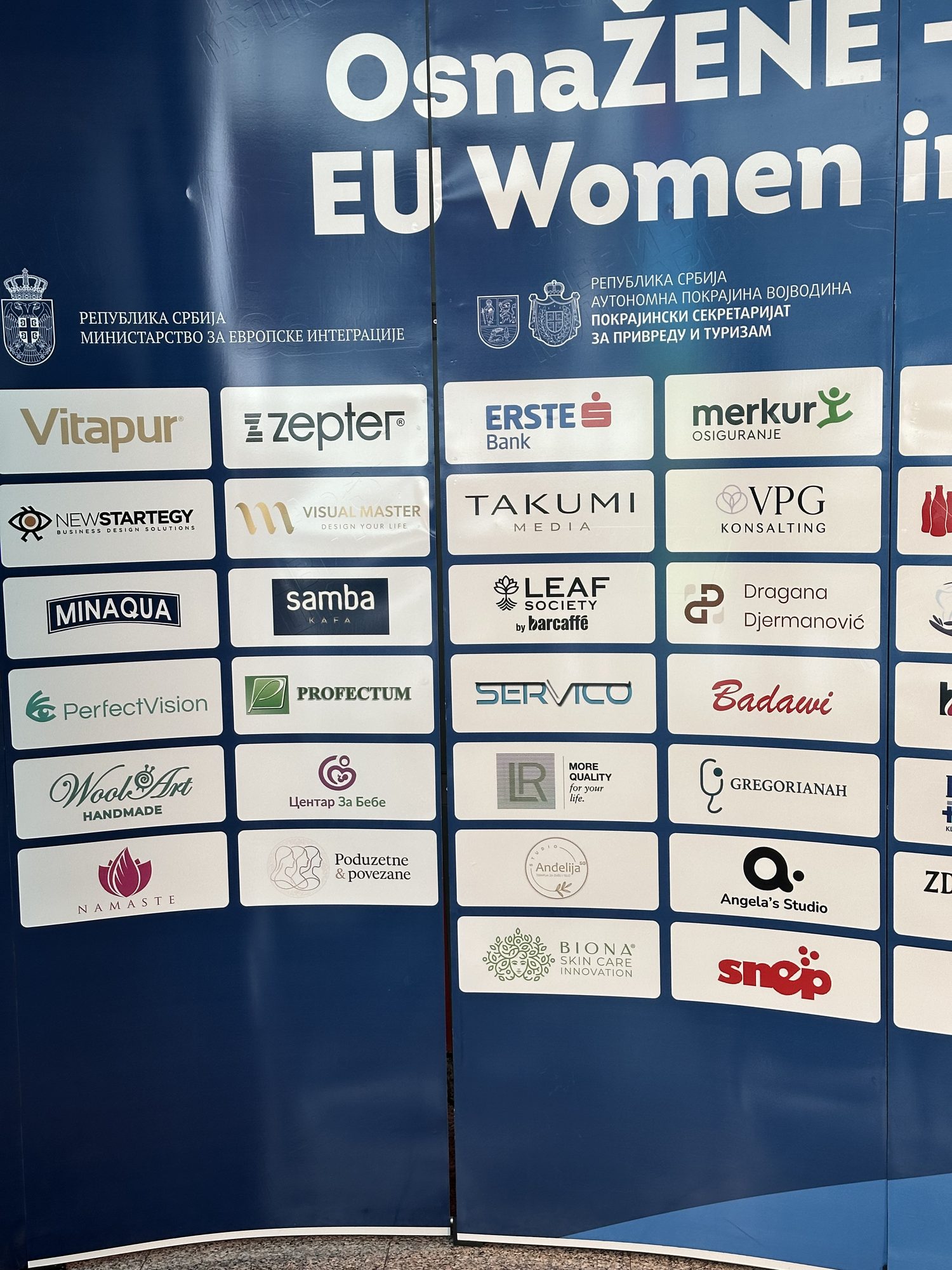 The exhibitor wall at the summit entrance, the Angela's Studio mark among the rows of company logos.