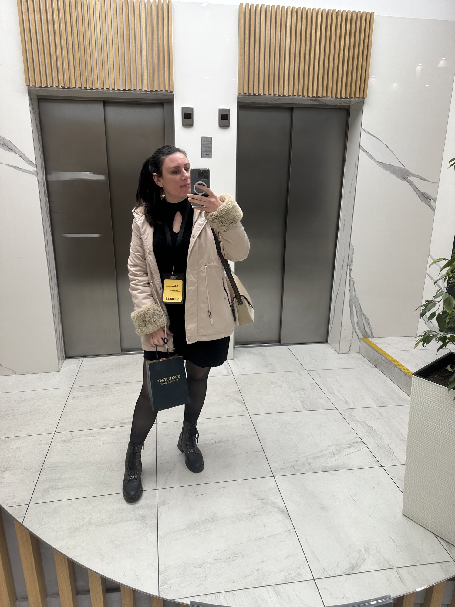 A mirror shot in the marble hotel lobby, badge around my neck and a paper bag in hand, the lift doors behind me.